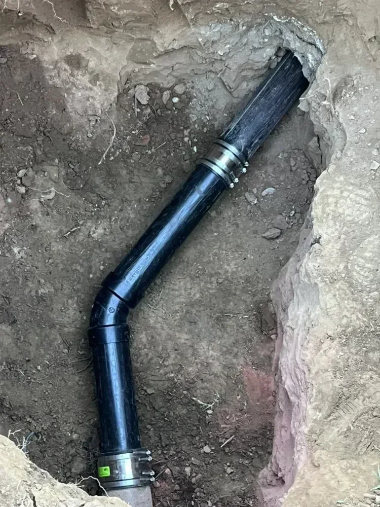 Exposed sewer pipe connection in an excavated trench